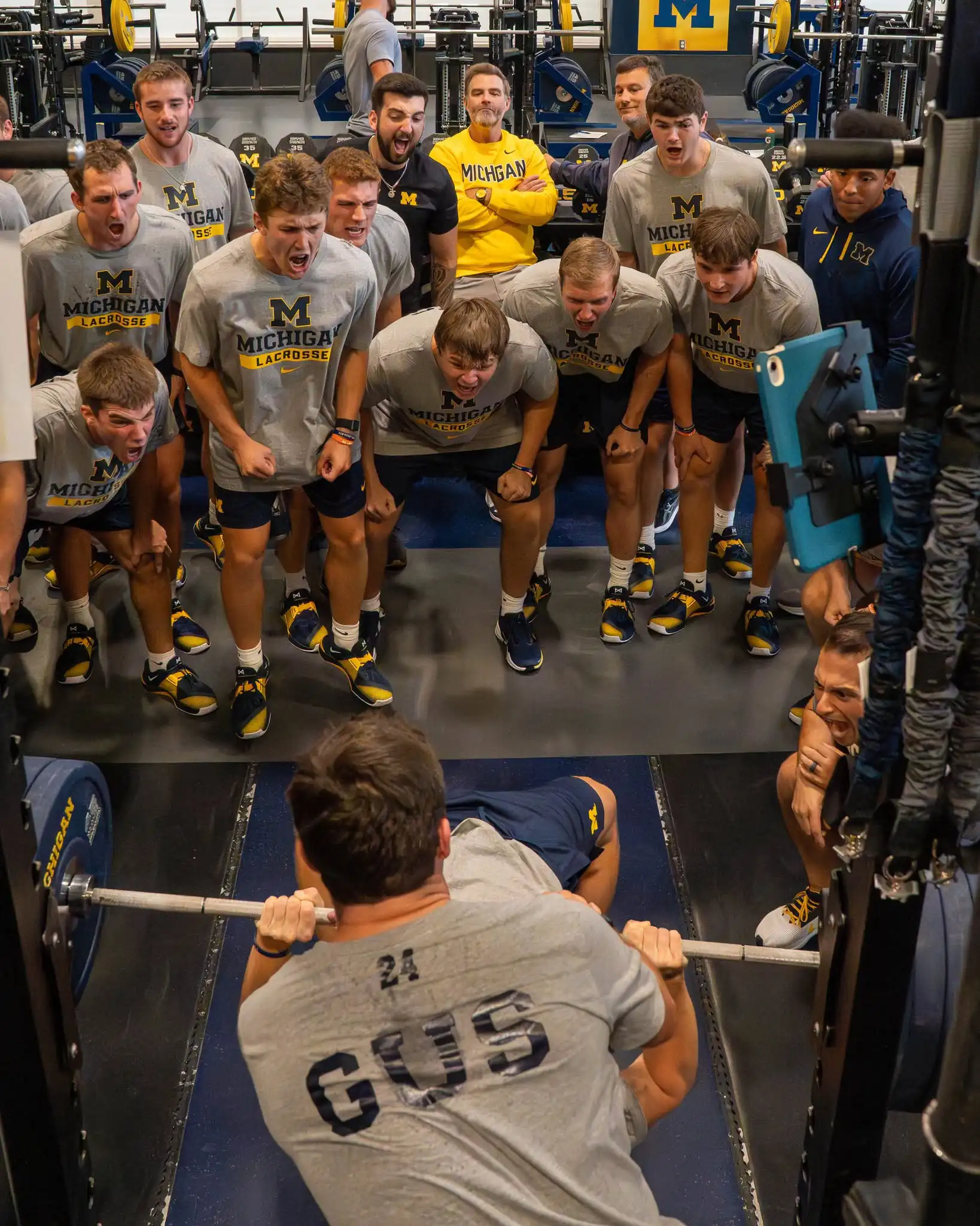 Krachttraining bij het lacrosseteam van de University van Michigan Lacrossespelers van de University of Michigan moedigen een teamgenoot aan tijdens een krachttraining in de fitnessruimte van de universiteit.