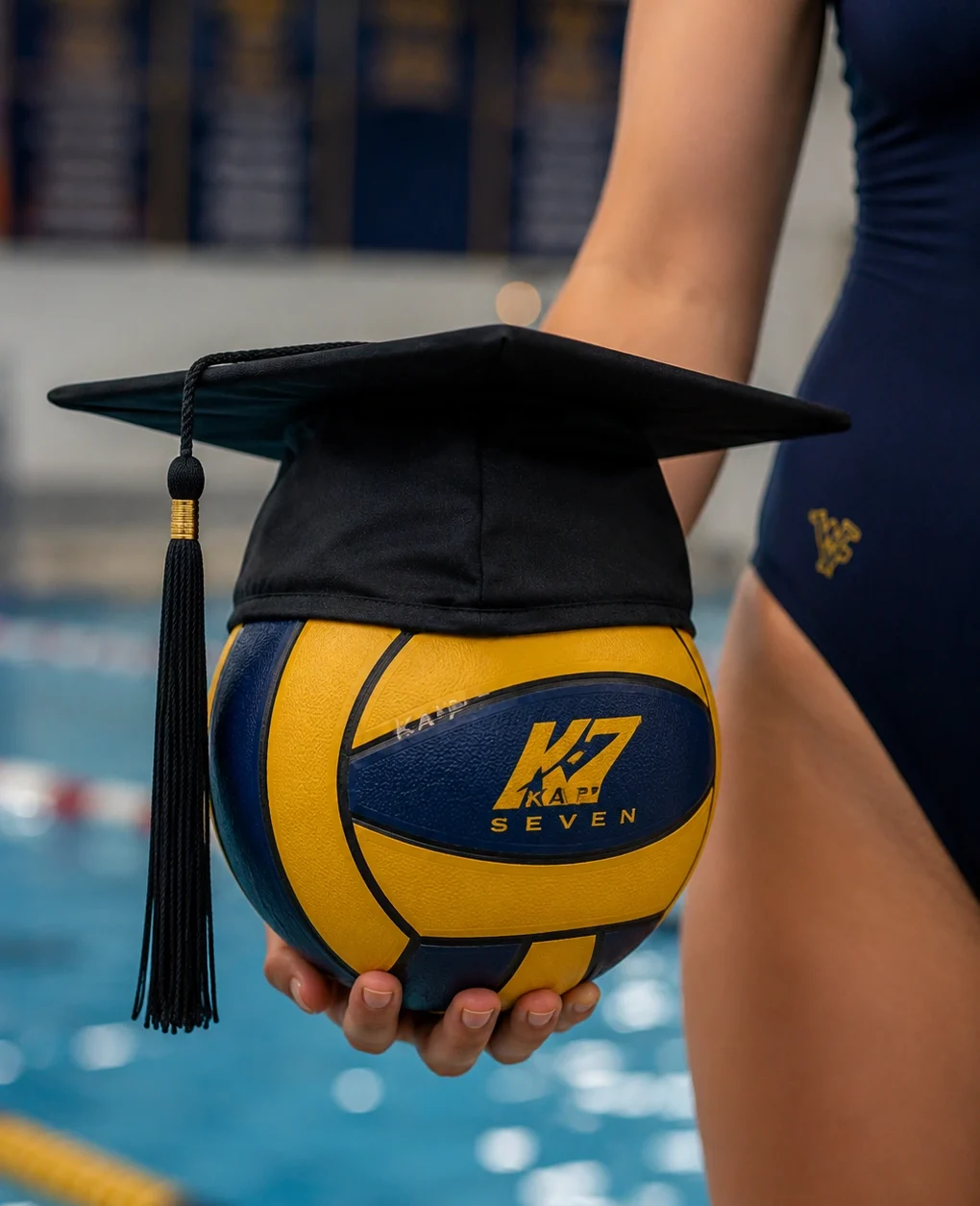 Waterpolo scholarship in Amerika: sport en studie combineren Waterpolobal met afstudeerhoed vastgehouden door een student-athlete bij een zwembad